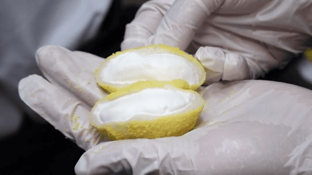 A person cutting a yellow rice cake in half