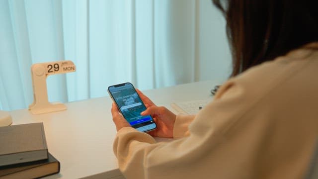 Woman using a smartphone at a desk in a calmly lit room