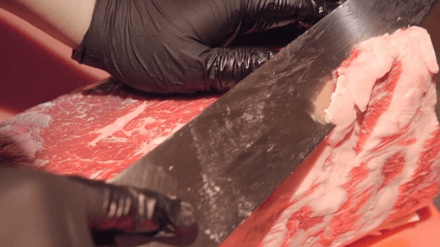 Slicing raw beef with a large knife