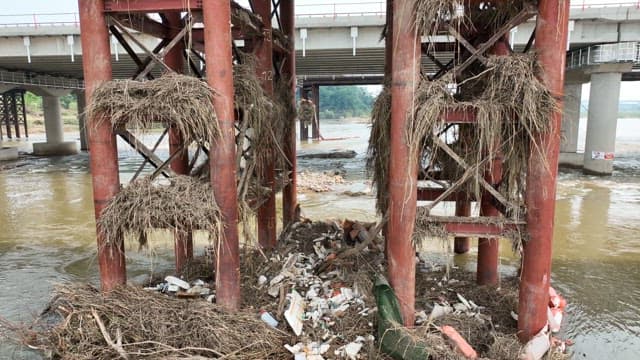 Debris Piled up on a River Bridge Structure Flooded by Heavy Rain