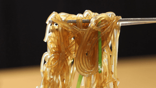 Japchae glass noodles held with chopsticks