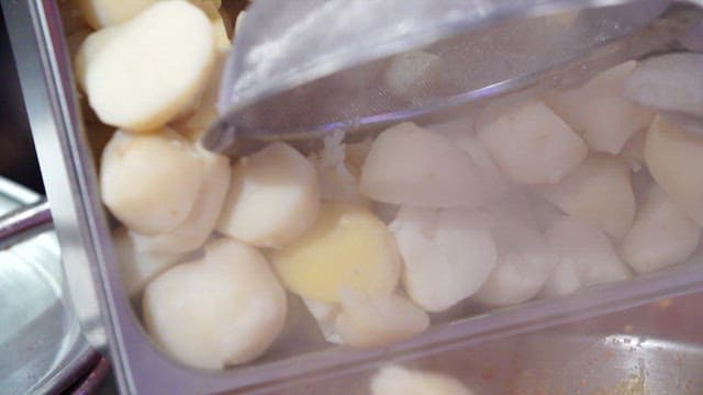 Boiled potatoes being added to a seasoning broth