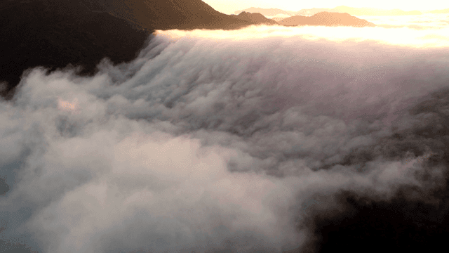Sunset setting over clouds crossing mountain peaks