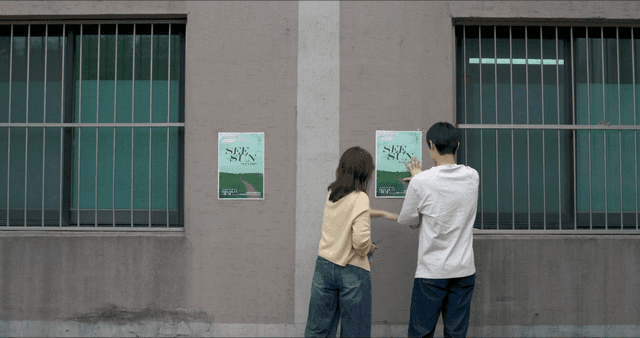 벽에 포스터를 붙이는 두 남녀