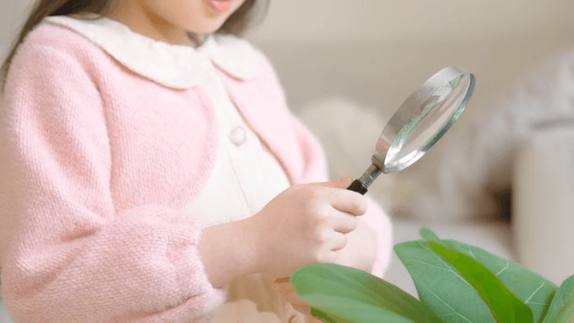 돋보기로 잎을 관찰하는 아이