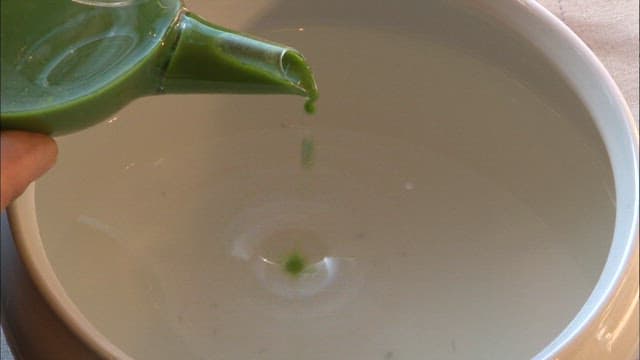 Pouring Green Color Tea Into a Cup on a Sunny Day