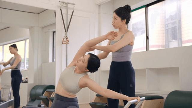 Pilates instructor guiding a student indoors