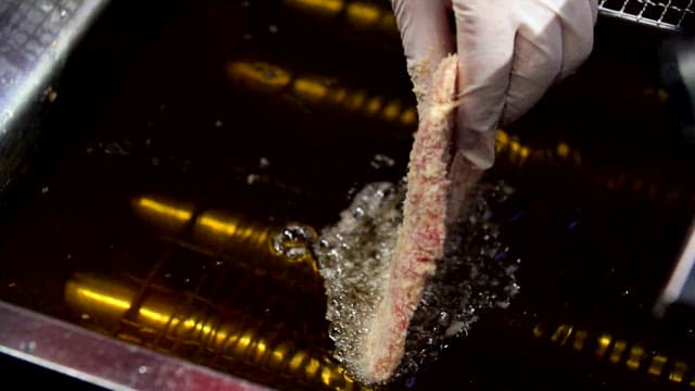 Breaded raw pork being fried in hot oil