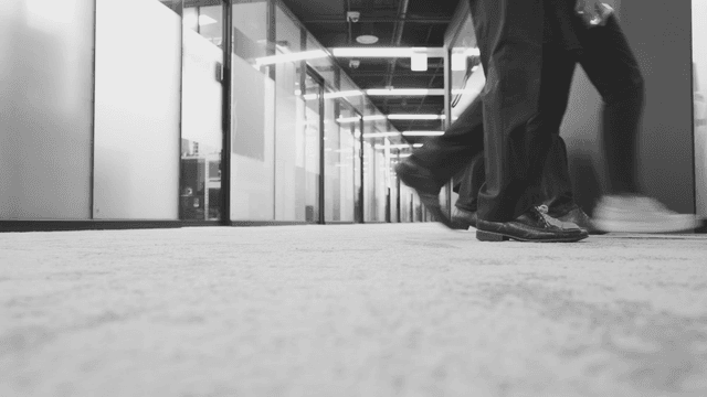 Three people walking in an office hallway