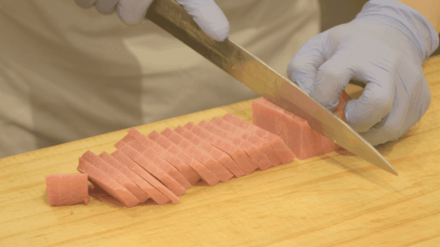 Chef cutting fresh tuna on cutting board