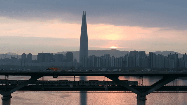 Train running through a city at dusk with high-rise towers