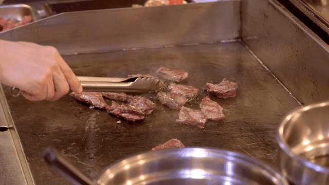 Chef grilling meat on a hot griddle