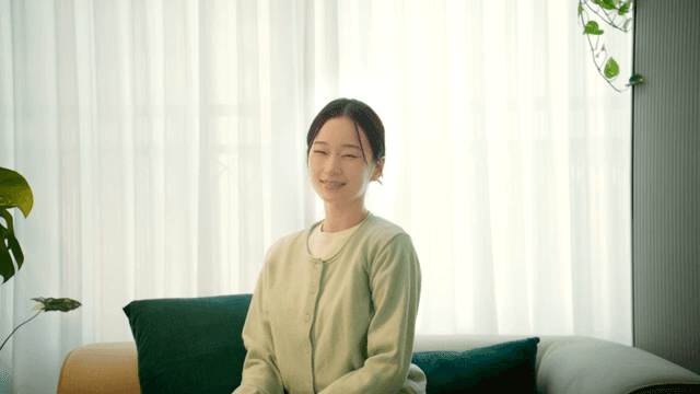 Woman sitting on living room sofa and smiling