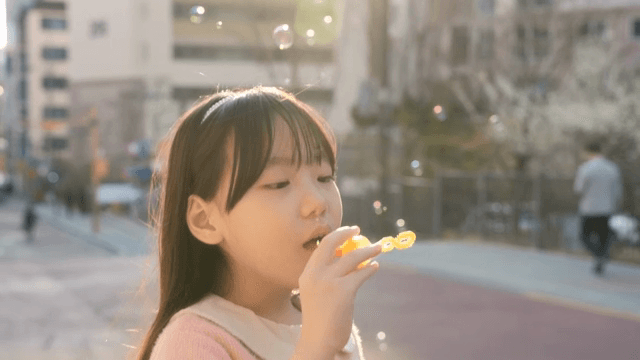 Child blowing bubbles on a sunny street