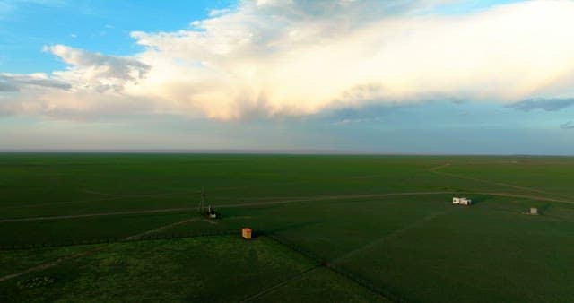 Vast green fields under a cloudy sky