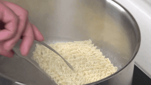 Ramen placed with tongs into a hot pot