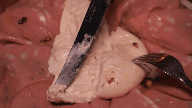 Scene of cutting burrata cheese with knife and fork