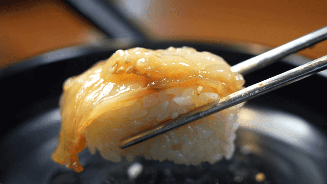 Chopsticks holding sushi with fish slice