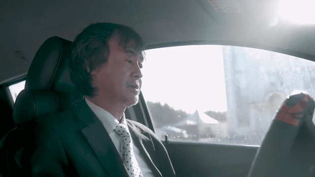 정장을 입은 남자가 차 안에 앉아 있는 모습