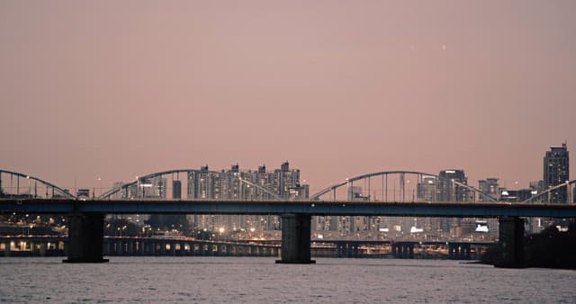 Bridge over river with evening cityscape in background