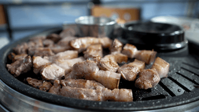Pork belly sizzling on grill