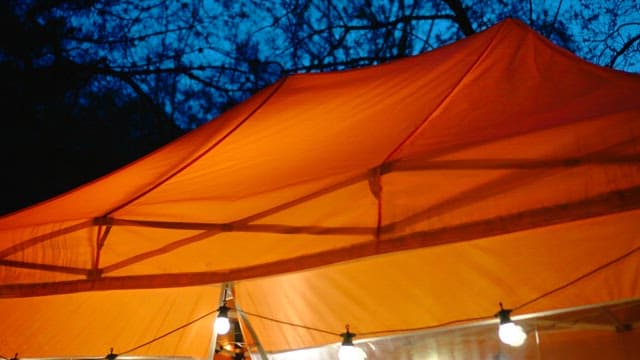 Orange tent awning illuminated by bulb lights at night