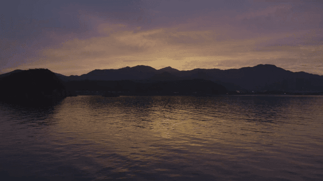 일몰에 산이 보이는 고요한 바다