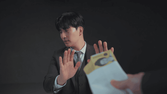 정장을 입은 남자가 봉투를 거절하는 모습