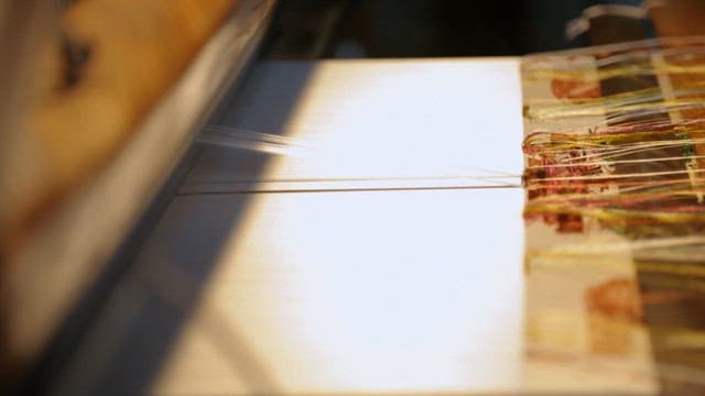 전통 베틀에서 색색의 실로 정교한 패턴을 짜는 숙련된 손길