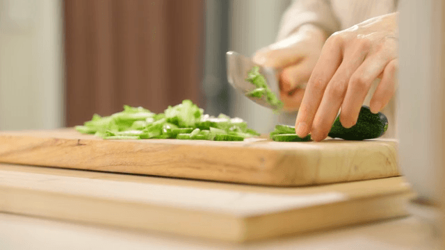 나무 도마 위에서 신선한 오이 자르기