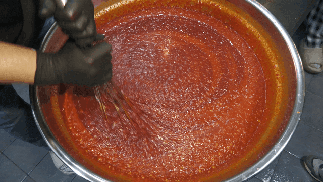 Mixing red sauce in a large pot