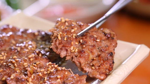 Grilled tteokgalbi with sesame seeds on a plate