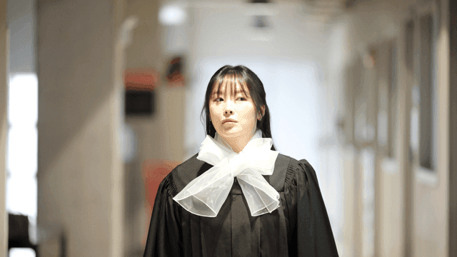 College students in graduation gowns in hallway