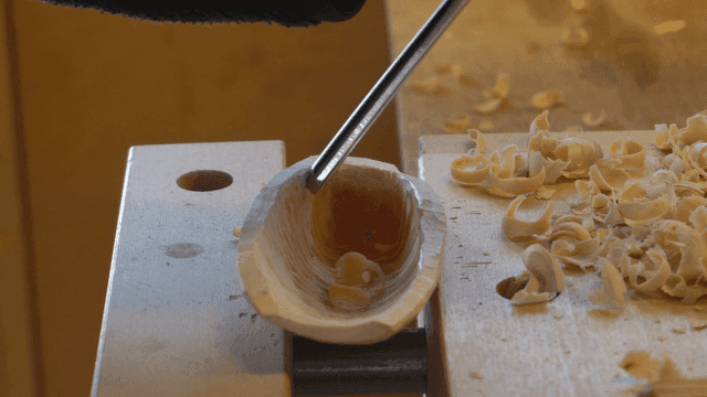 작업대 위에서 나무를 조각하는 장갑 낀 손