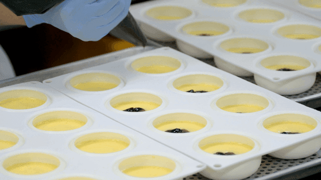 Pastry chef filling molds with cream and toppings