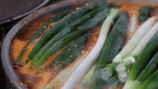 Green onions boiling in spicy broth
