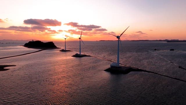 Wind turbines by the sea at sunset