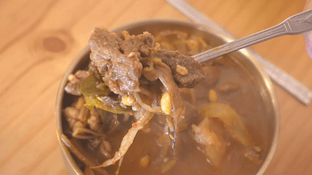 Serving spicy steaming Korean beef soup with spoon