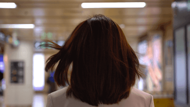 Back view of woman walking through crowded subway station