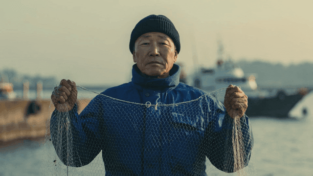 Old fisherman holding net in sea
