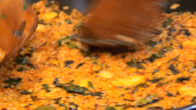 Glossy fried rice spread flat with spatula on iron plate