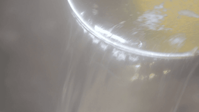 Clear meat broth pouring from ladle