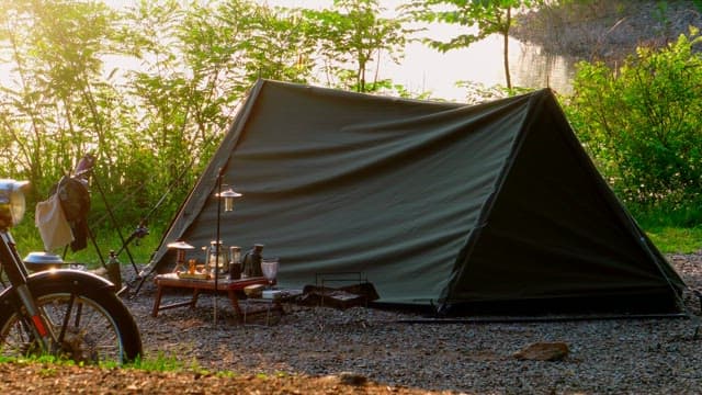 Tent setup and camping equipments by a lakeside in a forest on a sunny day