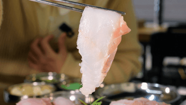 Fresh sashimi being picked up with chopsticks