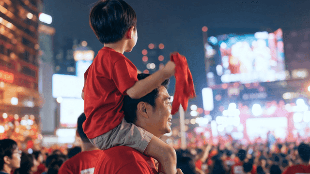 Father cheering for soccer while giving his son piggyback ride
