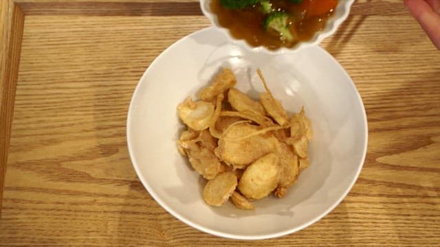 Pouring sweet and sour sauce over crispy ginseng chips