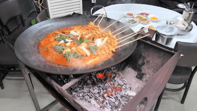 Pork belly stew with fish cake skewers on charcoal grill