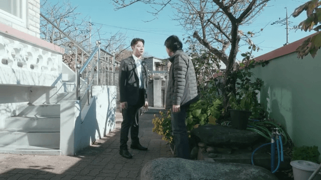 Two men talking with serious expressions in the yard