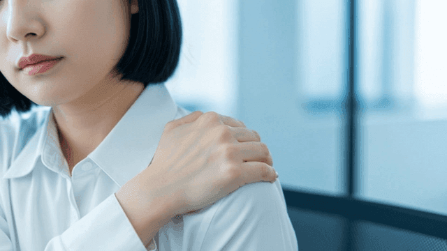 Female office worker clutching her shoulders in office