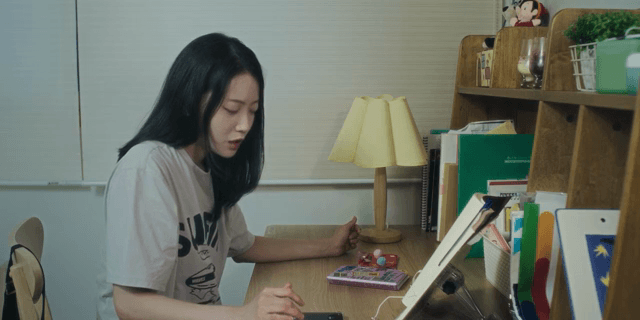 방 책상에 앉아 있다가 일어나는 여성